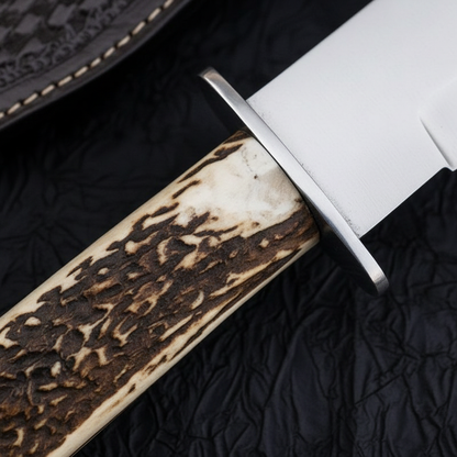 Extreme close-up of natural stag antler handle with steel crossguard on deep black charcoal background