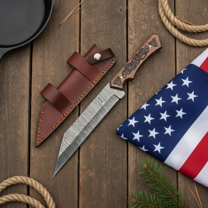 Damascus steel Seax knife and brown leather sheath on dark brown wood with a USA flag positioned beside the product