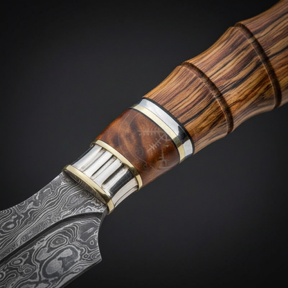 Close-up of the natural wood handle with silver bolster and brass spacers on a Damascus steel knife