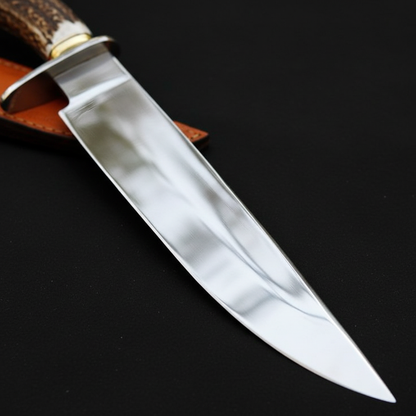Extreme close-up of mirror polished carbon steel Bowie blade clip point on black charcoal background