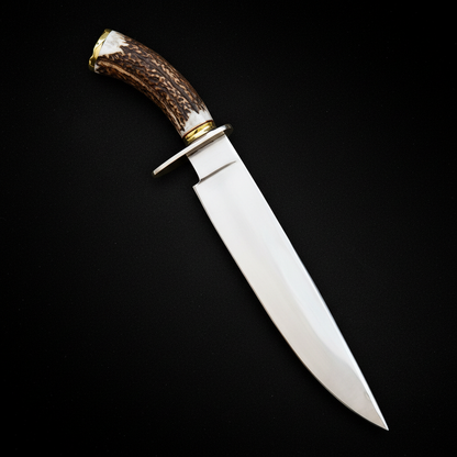 Carbon steel Bowie knife stag antler handle brass bolster studio shot centered on deep black charcoal background