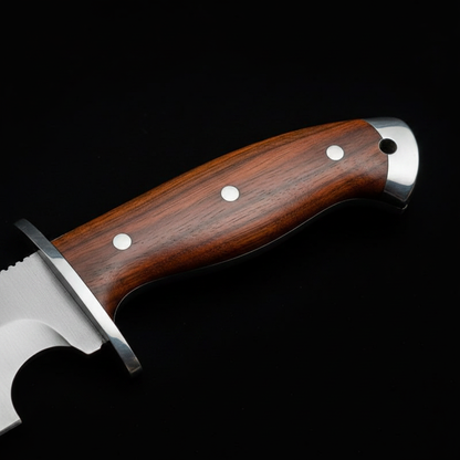 Close view of the natural rosewood Bowie handle with metal guard, sub hilt contour, steel pins, and pommel