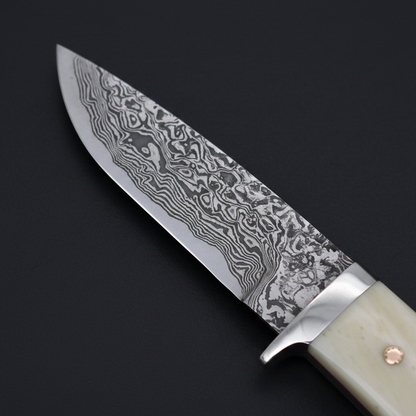 Extreme close-up of flowing Damascus steel pattern on drop point blade with charcoal background