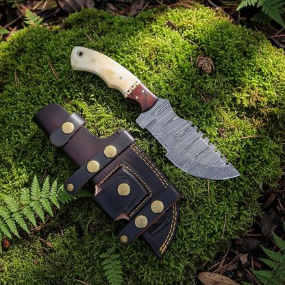 Damascus camel bone rosewood tracker knife and leather sheath on lush green forest moss natural outdoor setting