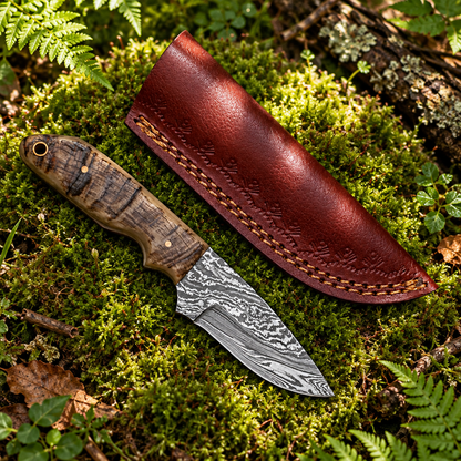 Handmade Damascus skinner knife wild pattern blade ram horn handle and burgundy embossed leather sheath on thick green forest moss natural outdoor