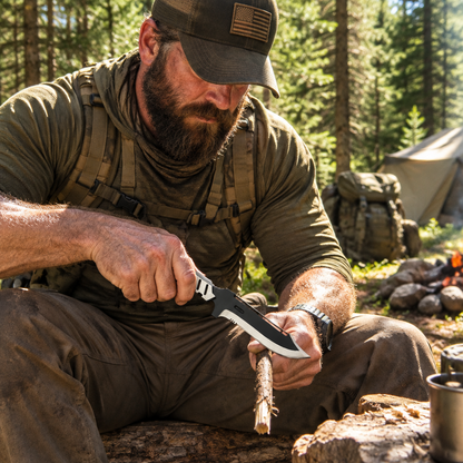 Rugged bearded outdoorsman looking down holding MGS4 Old Snake replica tactical knife at sunny forest campsite