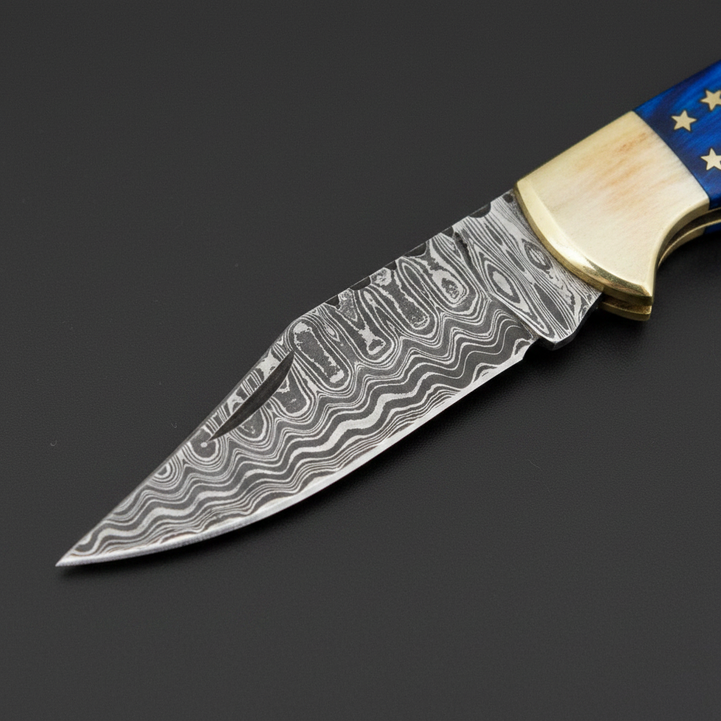Close-up of the patterned Damascus blade and brass bolster on a black-charcoal background