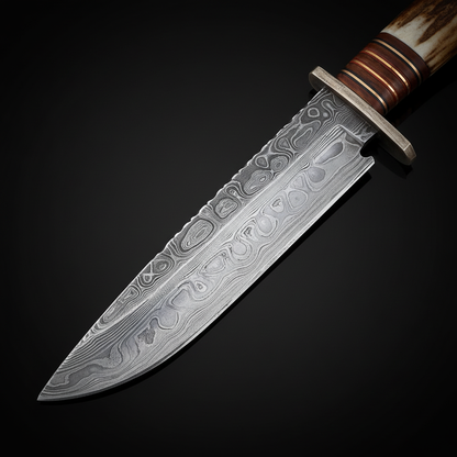 Close view of the Damascus Bowie hunting blade with fuller, spine filework, and part of the stag antler handle