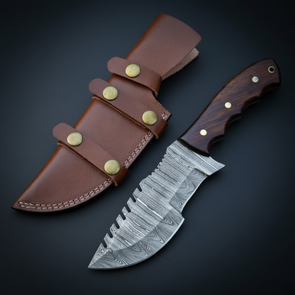 Angled Damascus steel tracker knife and leather sheath photographed on near-black charcoal background
