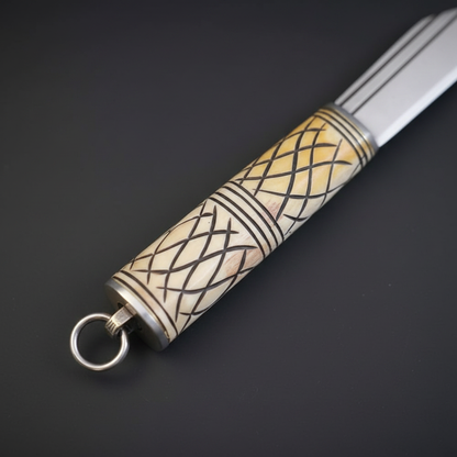 Close view of the carved camel bone handle with brass fittings and lanyard ring