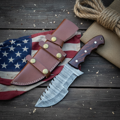 Damascus tracker hunting knife and leather sheath arranged on dark brown wood beside a USA flag