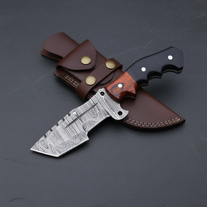 Damascus tracker hunting knife and leather sheath arranged on dark charcoal slate
