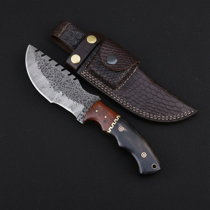 Damascus tracker knife and leather sheath on a black background